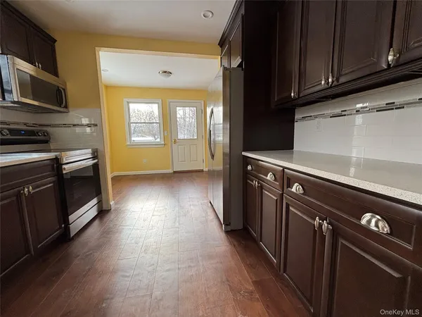 a kitchen with granite countertop wooden cabinets stainless steel appliances and a window
