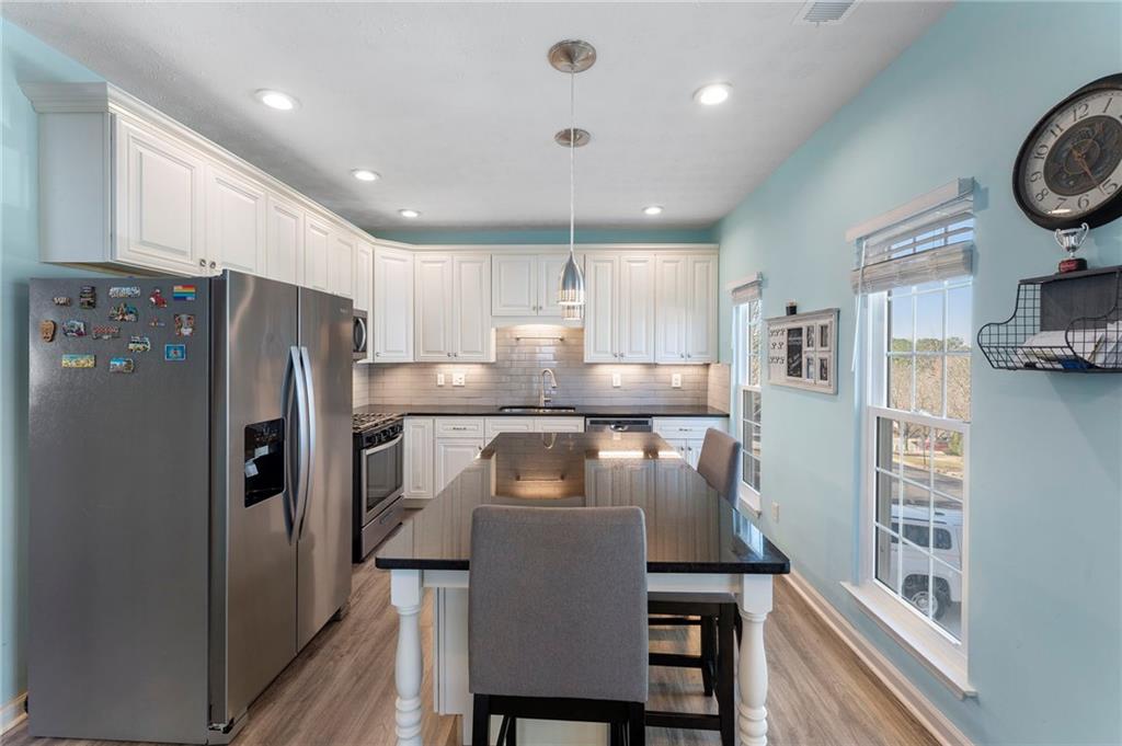 a kitchen with stainless steel appliances granite countertop a refrigerator a stove a sink and a cabinets