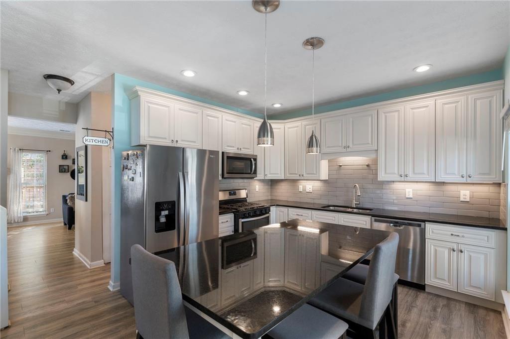 4074 Spring Cove Drive Duluth, GA 30097 - Photo 18 of 48 a kitchen with stainless steel appliances granite countertop a refrigerator a sink dishwasher a stove and white cabinets with wooden floor