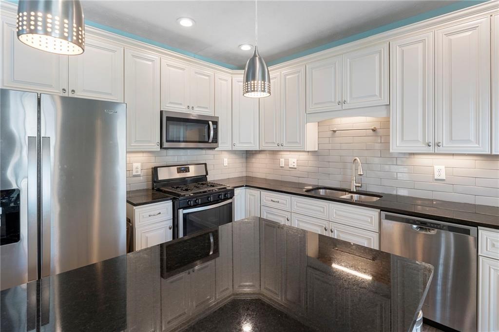 4074 Spring Cove Drive Duluth, GA 30097 - Photo 20 of 48 a kitchen with granite countertop a refrigerator stove and microwave