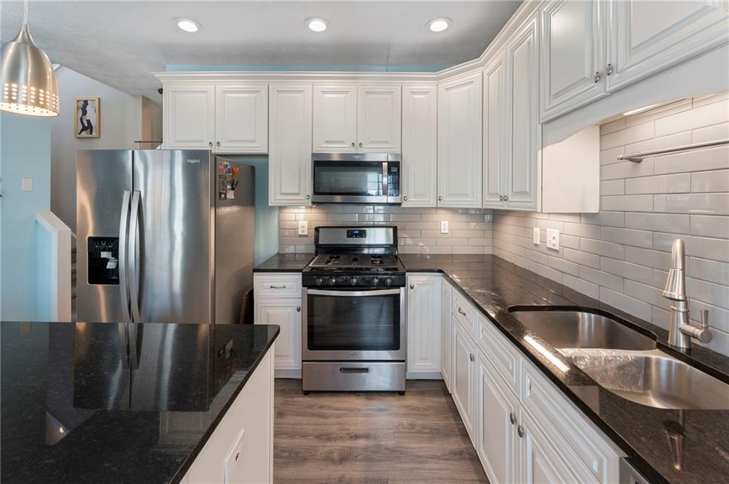 4074 Spring Cove Drive Duluth, GA 30097 - Photo 21 of 48 a kitchen with granite countertop a sink stainless steel appliances and cabinets