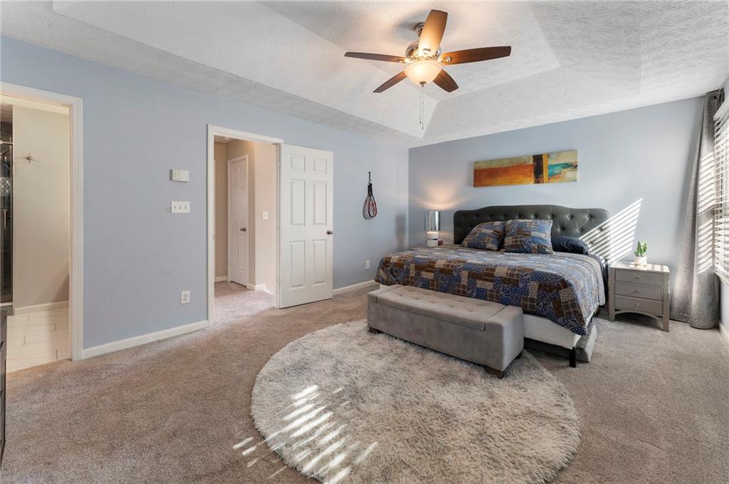 4074 Spring Cove Drive Duluth, GA 30097 - Photo 27 of 48 a spacious bedroom with a bed and a chandelier