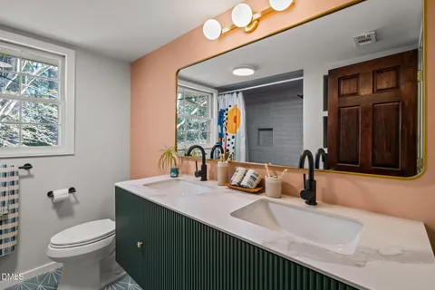 a bathroom with a sink double vanity granite and a toilet