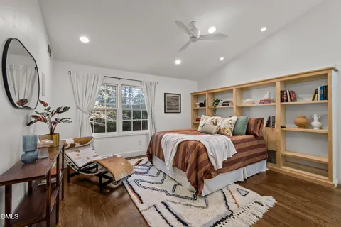 a spacious bedroom with a bed a desk and chair with the wooden floor