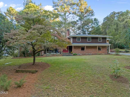 a view of a house with a yard and large tree