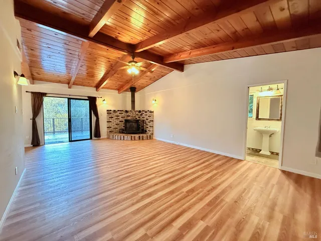 a view of an empty room with wooden floor and a fireplace
