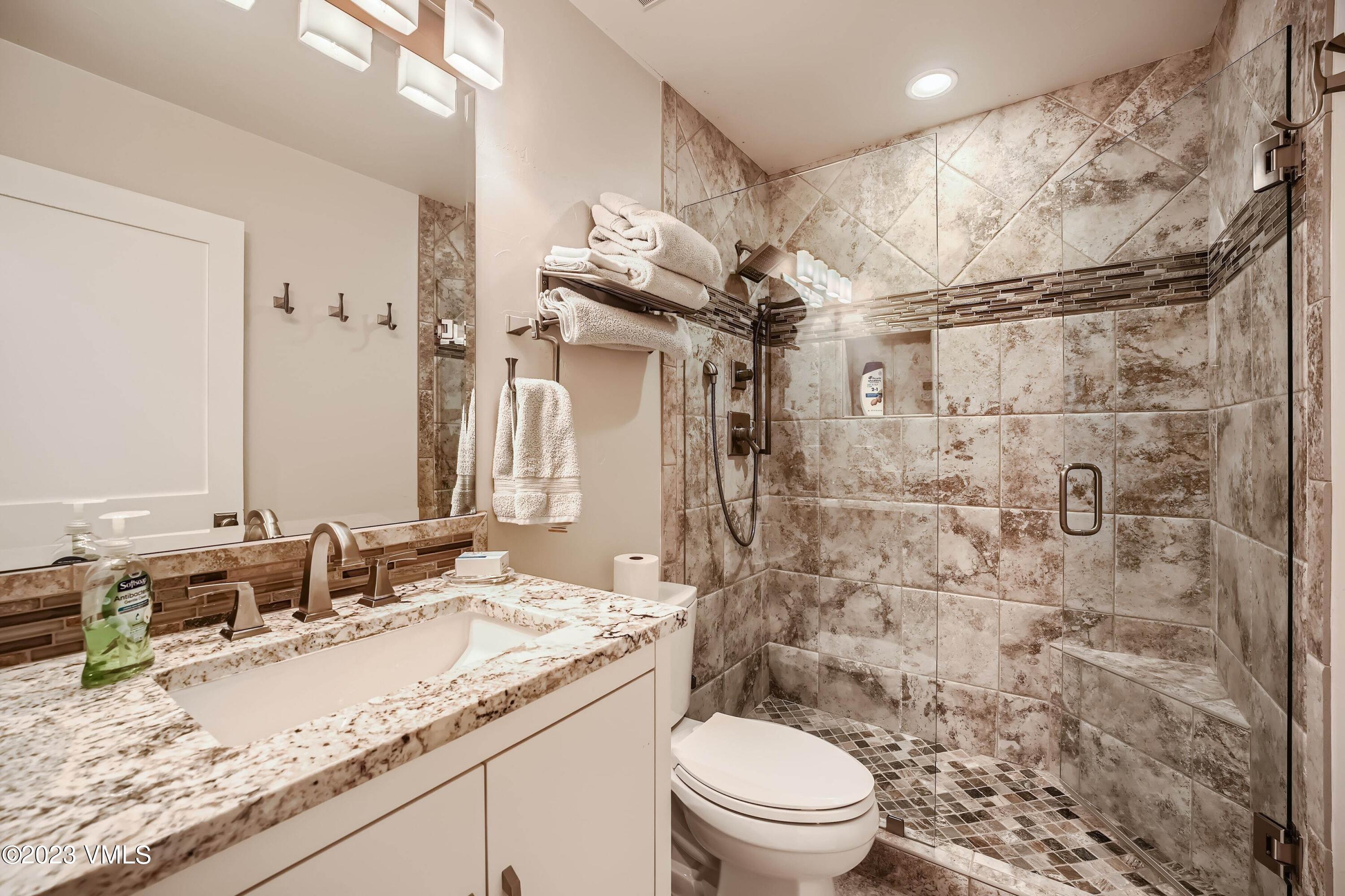 1030 Lions Ridge Loop, Unit 202 Vail, CO 81657 - Photo 14 of 25 a bathroom with a granite countertop sink toilet mirror and shower
