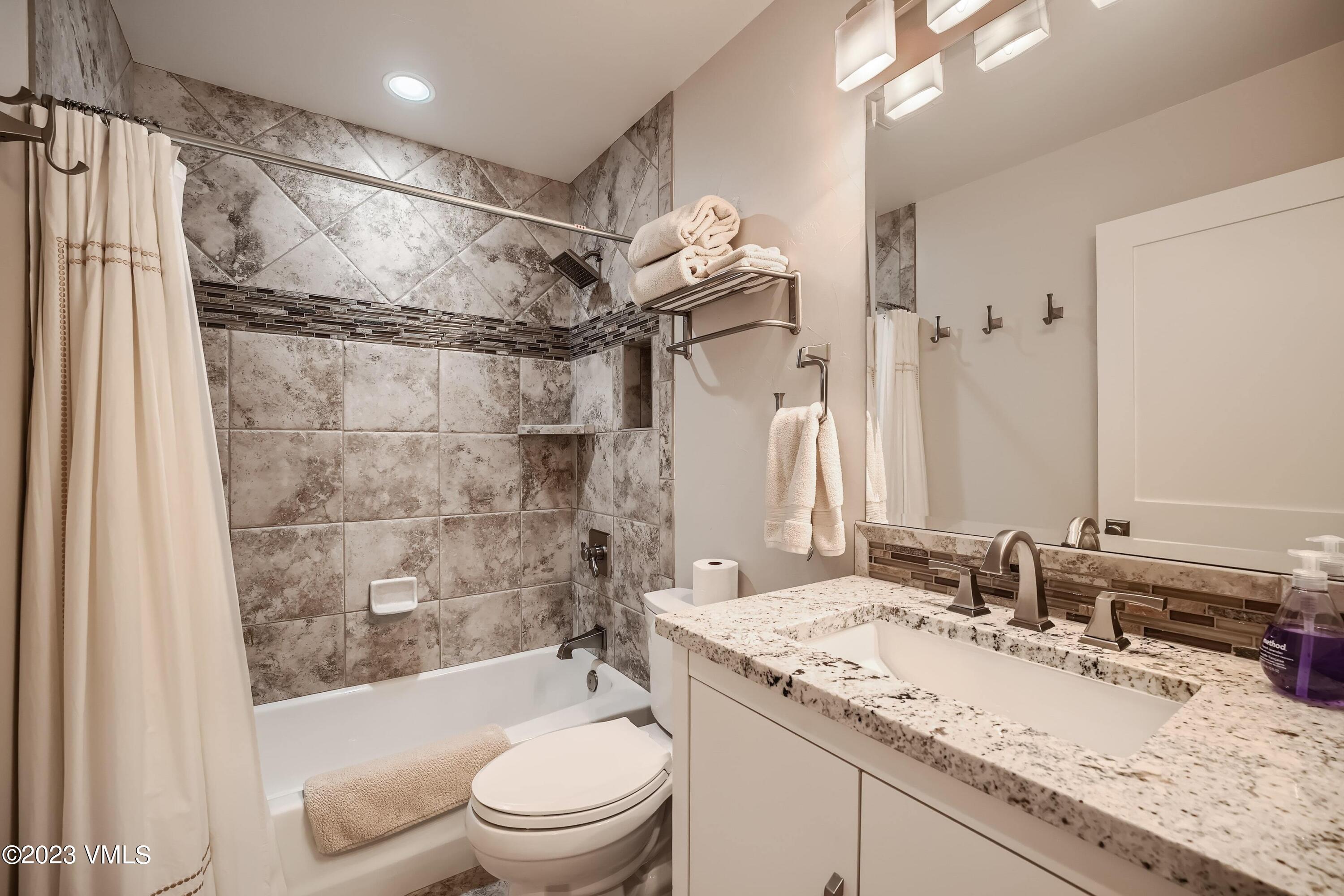 1030 Lions Ridge Loop, Unit 202 Vail, CO 81657 - Photo 18 of 25 a bathroom with a granite countertop sink toilet and shower
