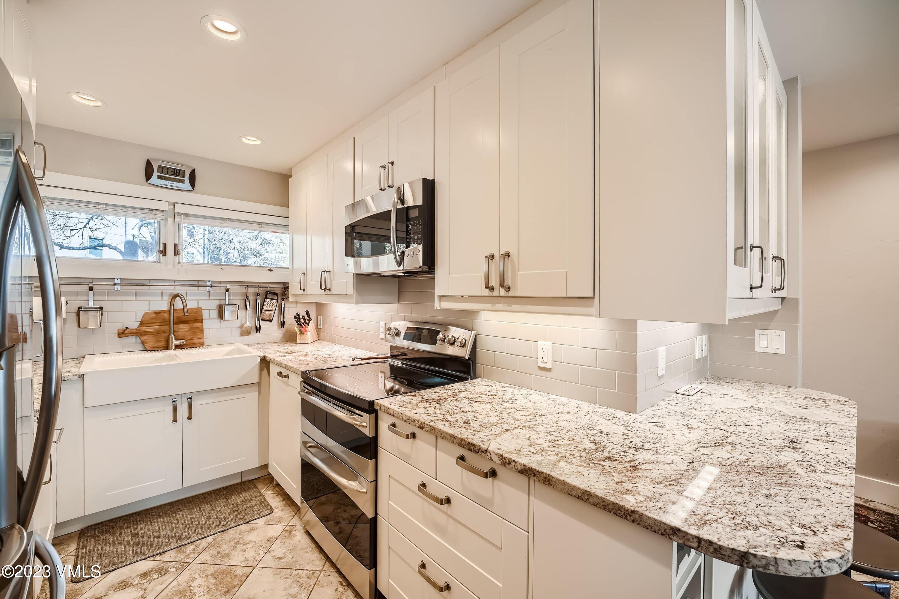 1030 Lions Ridge Loop, Unit 202 Vail, CO 81657 - Photo 10 of 25 a kitchen with granite countertop white cabinets and white appliances