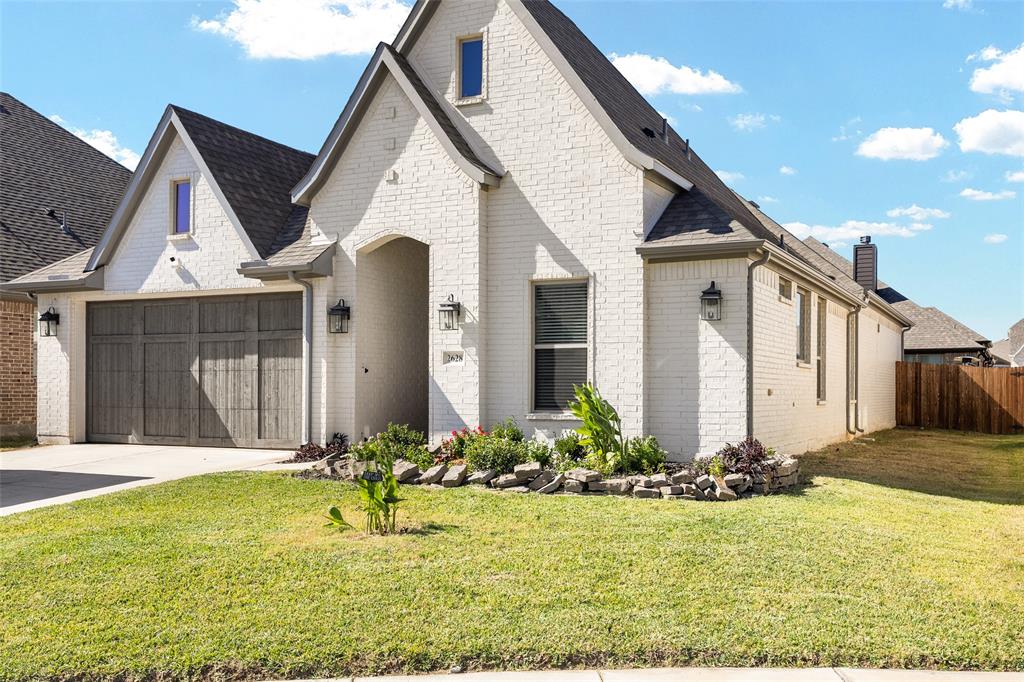 French country style house featuring brick siding, driveway, roof with shingles, and an attached garage