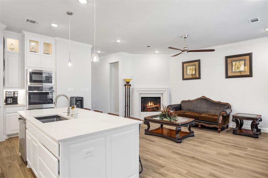 2628 Flycatcher Road Fort Worth, TX 76118 - Photo 34 of 38 Kitchen featuring open floor plan, ornamental molding, light wood-type flooring, white cabinetry, and stainless steel appliances