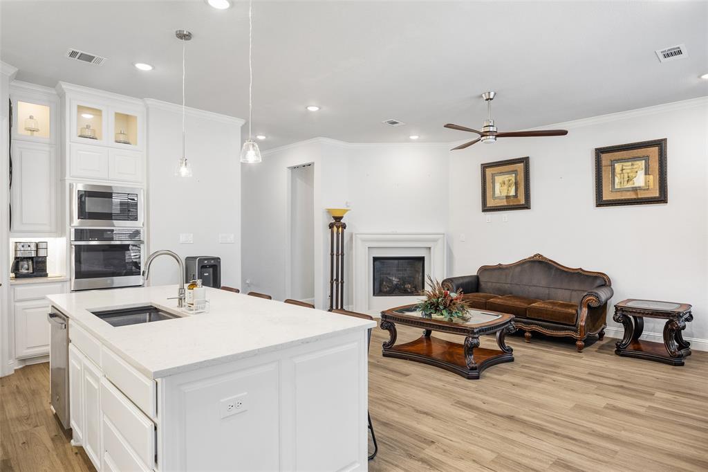 2628 Flycatcher Road Fort Worth, TX 76118 - Photo 35 of 38 Kitchen featuring open floor plan, crown molding, light wood-type flooring, white cabinetry, and stainless steel oven