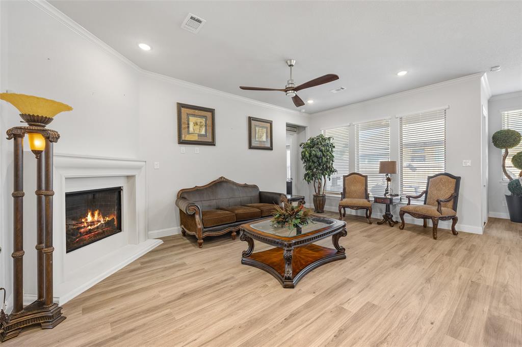 2628 Flycatcher Road Fort Worth, TX 76118 - Photo 6 of 38 Living area with light wood-type flooring, crown molding, recessed lighting, ceiling fan, and a warm lit fireplace