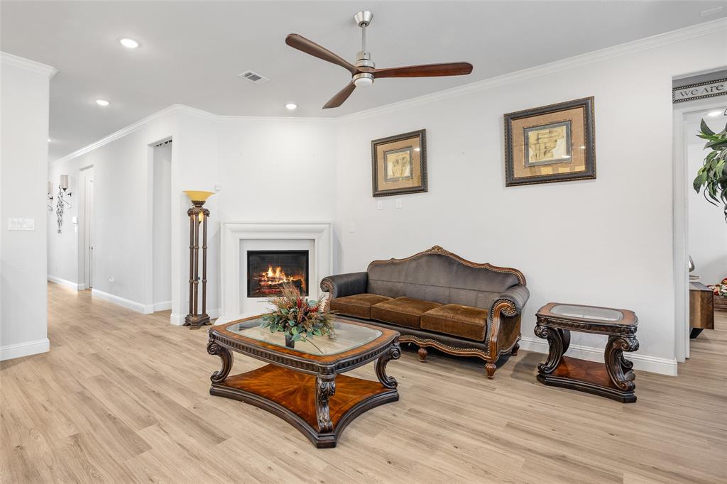 2628 Flycatcher Road Fort Worth, TX 76118 - Photo 7 of 38 Living area featuring a lit fireplace, crown molding, light wood-style floors, ceiling fan, and recessed lighting