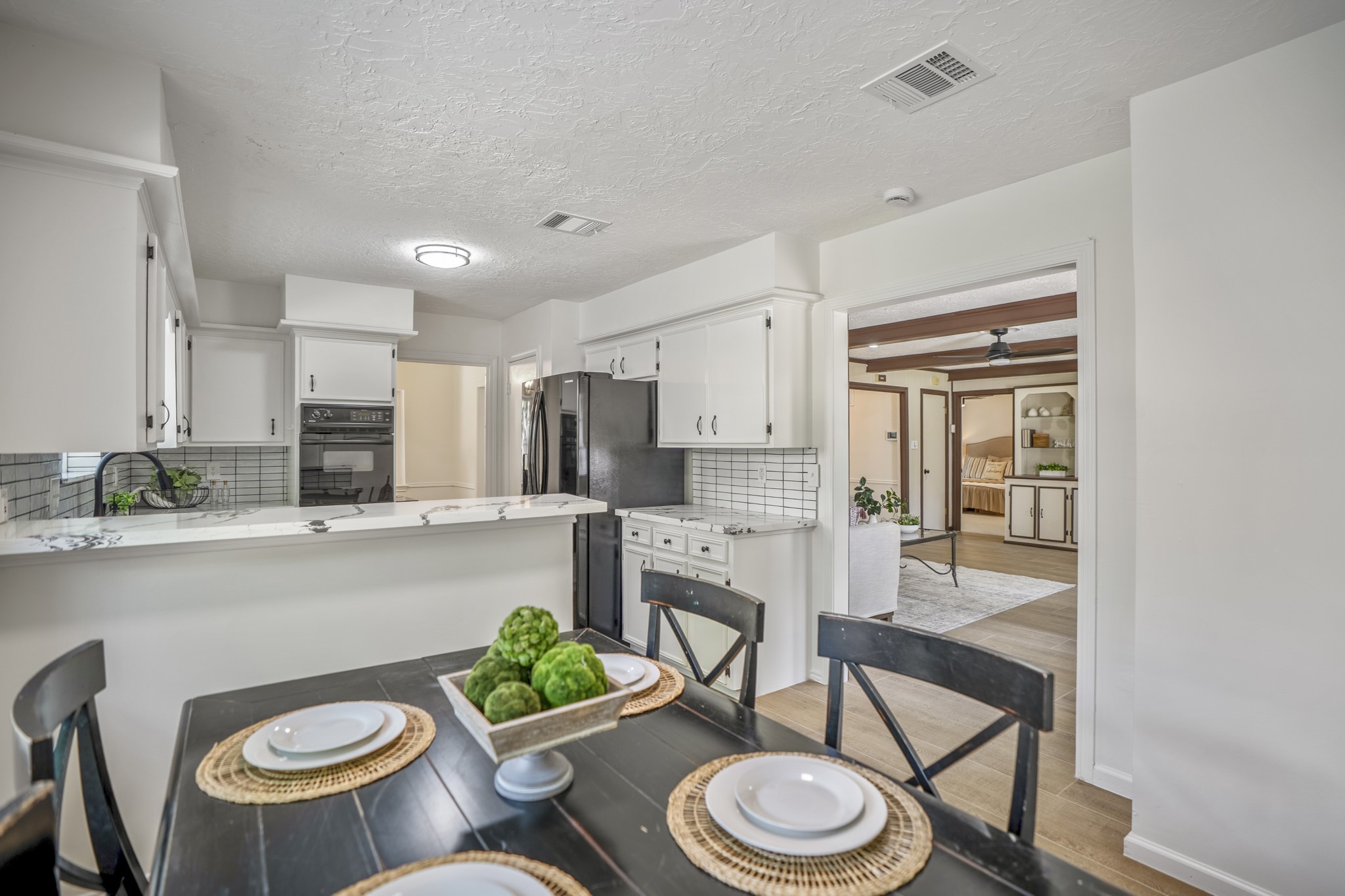 6303 Larkmount Drive Spring, TX 77389 - Photo 16 of 50 Looking back from the breakfast area, the kitchen’s peninsula creates a natural gathering spot with seating at the raised breakfast bar and clear views across the updated space. For the first time, we also catch a clearer glimpse into the family room beyond, offering a preview of the larger gathering space waiting at the back of the home.