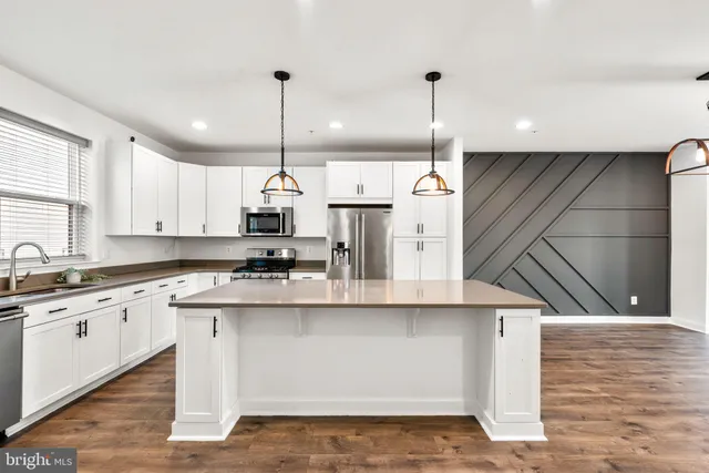 a kitchen with kitchen island granite countertop a sink a counter top space cabinets and stainless steel appliances