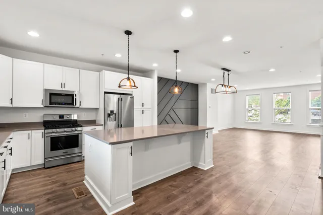 a kitchen with stainless steel appliances granite countertop a sink a stove and a wooden floors