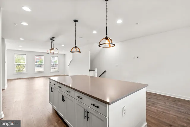 a open kitchen with a sink a center island and wooden floor