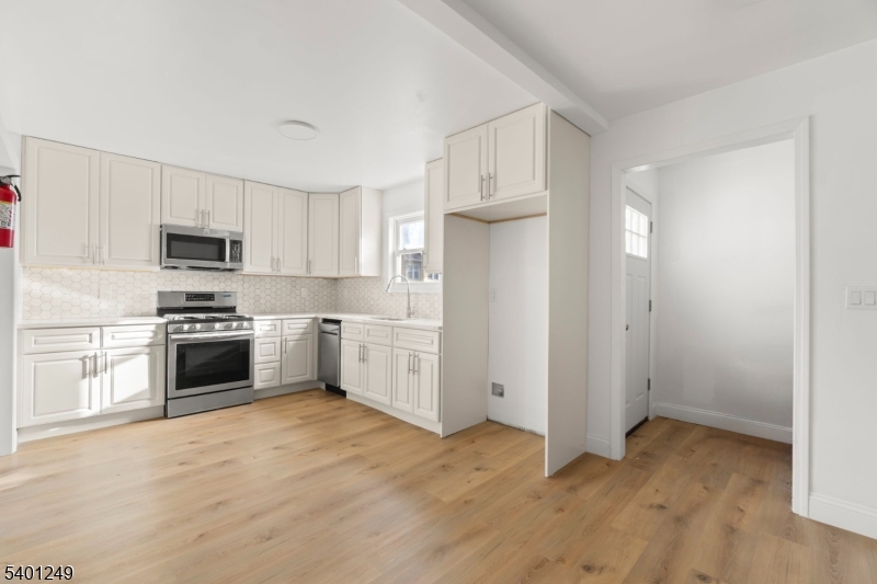 390 Clinton Place Newark, NJ 07112 - Photo 5 of 17 a kitchen with granite countertop white cabinets and stainless steel appliances