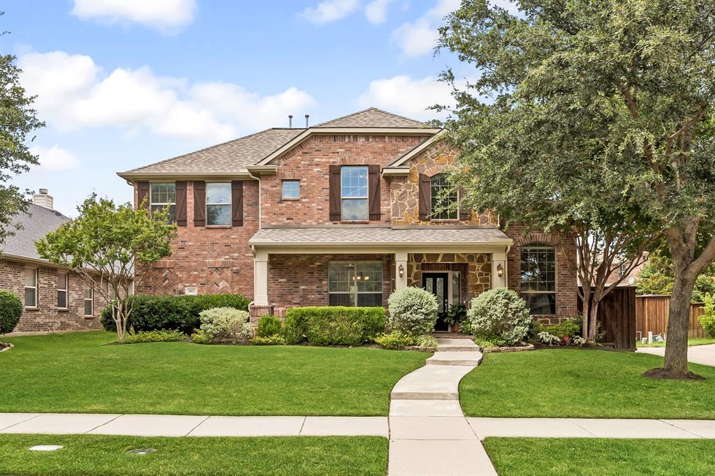 Brick and stone facade residence featuring a covered front porch with columns