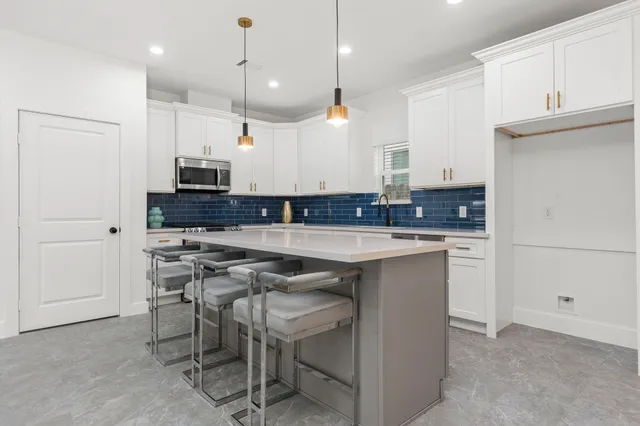 a kitchen with kitchen island granite countertop a sink a counter space appliances and cabinets