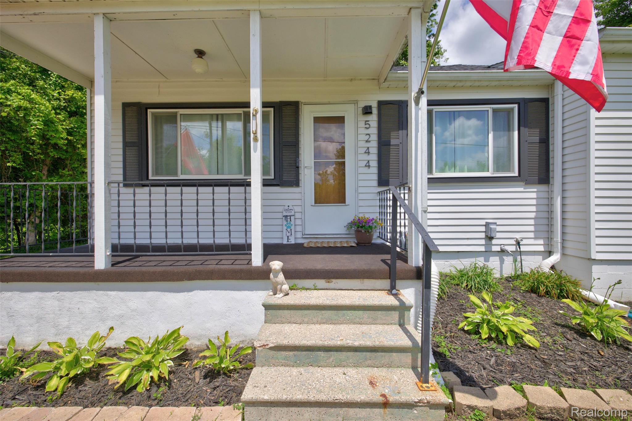 5244 Oleksyn Road Flint, MI 48504 - Photo 4 of 70 Front facade featuring white siding, a covered porch, dark shutters, and a concrete stairway with a metal railing