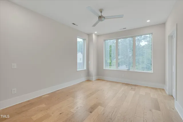 a view of an empty room with a window and wooden floor