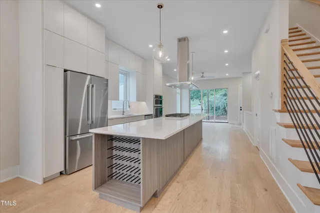 a large kitchen with kitchen island a large counter top a sink stainless steel appliances and cabinets