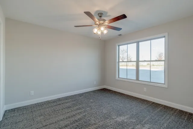 an empty room with wooden floor fan and windows