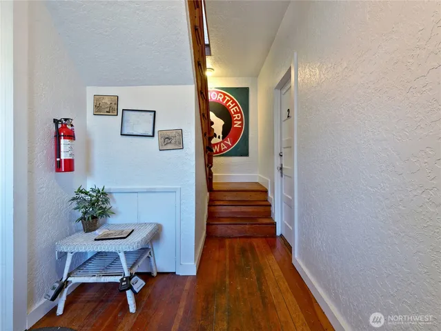 a view of a hallway with wooden floor and a potted plant
