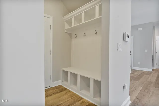 a view of an empty room with wooden floor and a bathroom