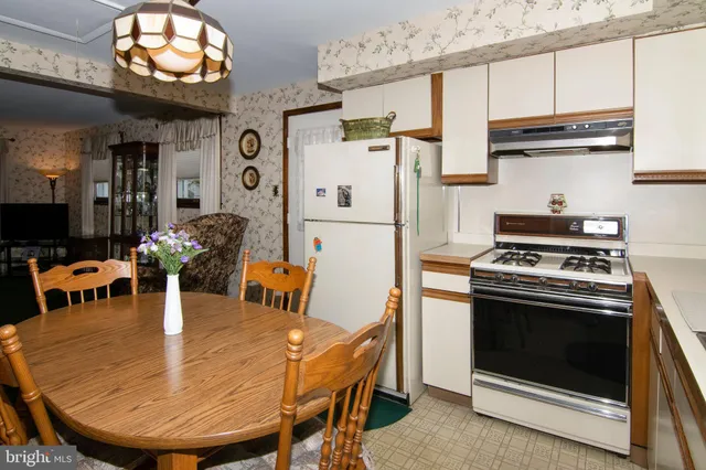 a kitchen with stainless steel appliances granite countertop a table chairs and a refrigerator