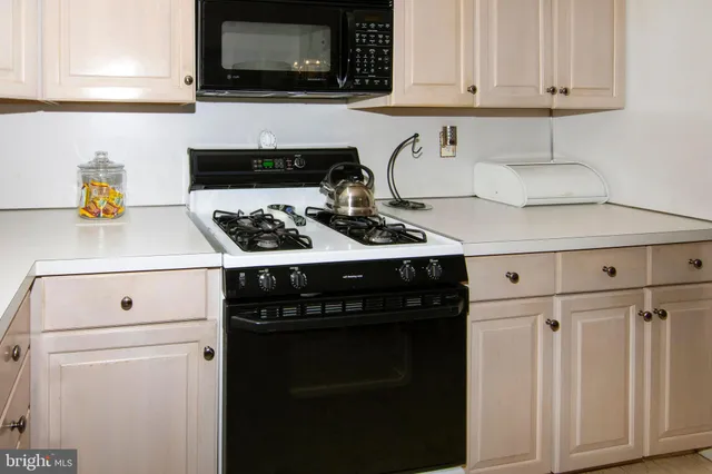 a kitchen with white cabinets and black appliances