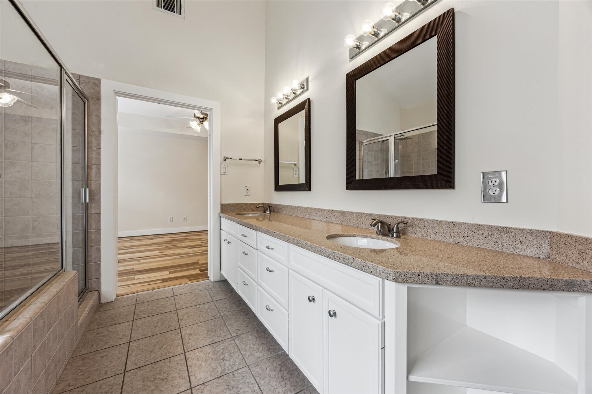 9829 Riddlelink Lane Houston, TX 77025 - Photo 12 of 22 Dual sinks, extended countertop space, and framed mirrors make getting ready easy in this spacious en suite bathroom.