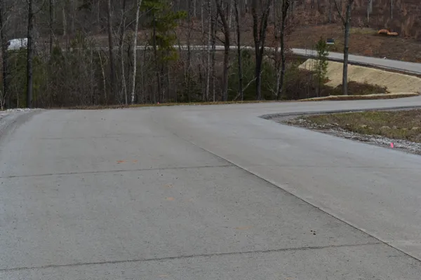 a view of a street with an empty space and trees in the background