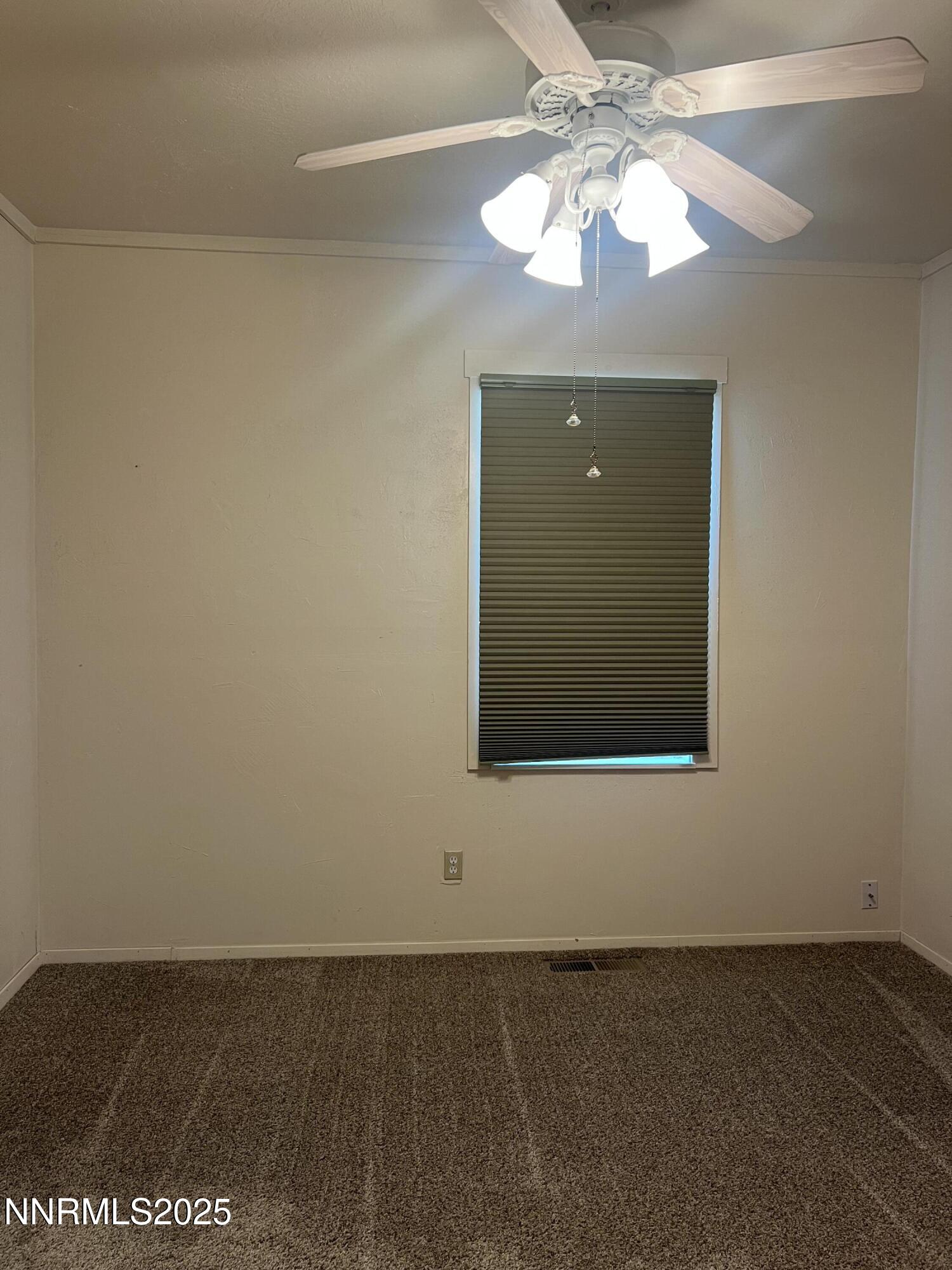 16 Tucker Lane Yerington, NV 89447 - Photo 9 of 12 an empty room with a chandelier fan and windows