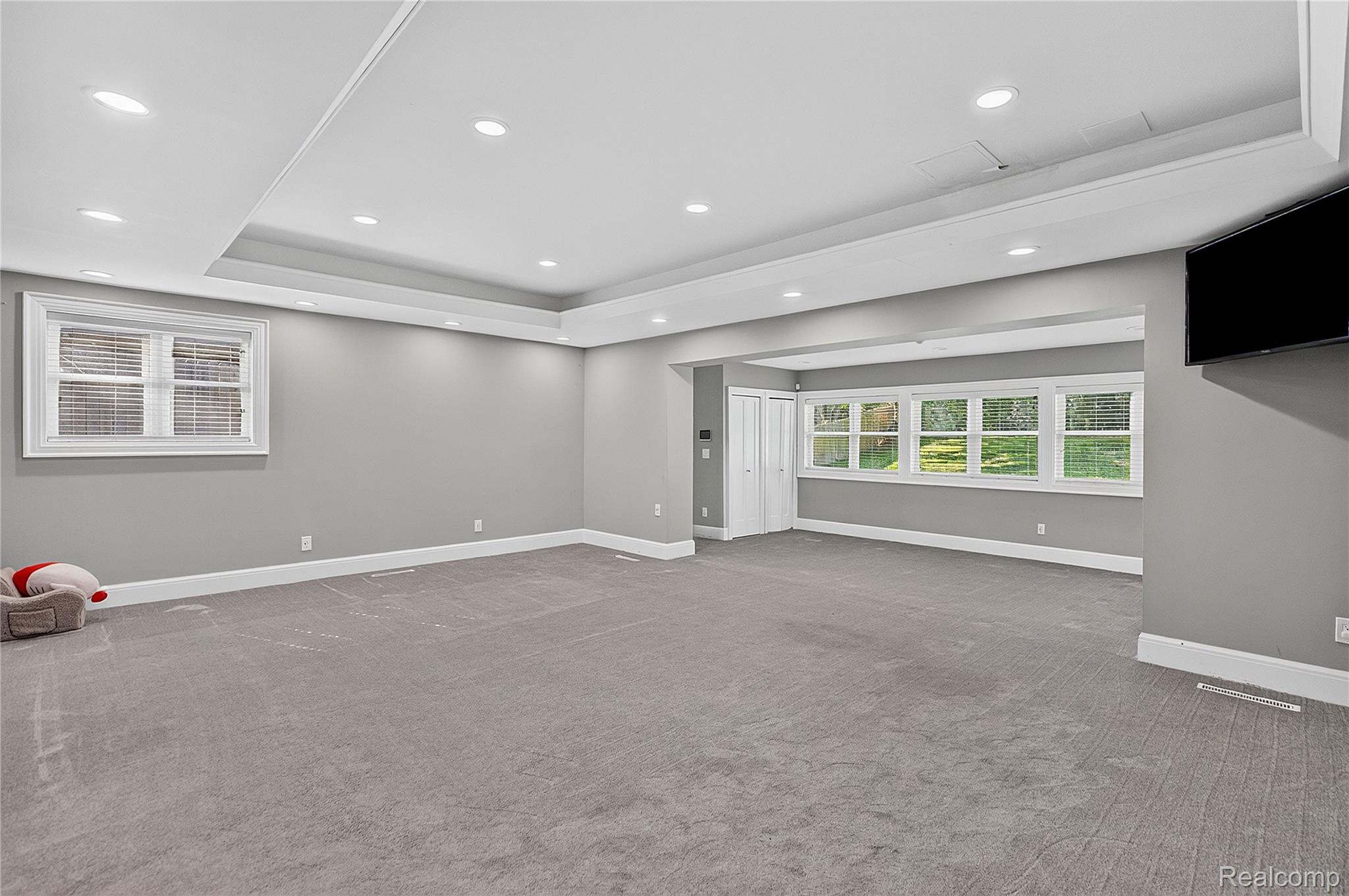 15879 Millar Road Clinton Township, MI 48036 - Photo 14 of 65 Recessed lighting, gray carpeting, tray ceiling, multiple windows, and a wall-mounted television