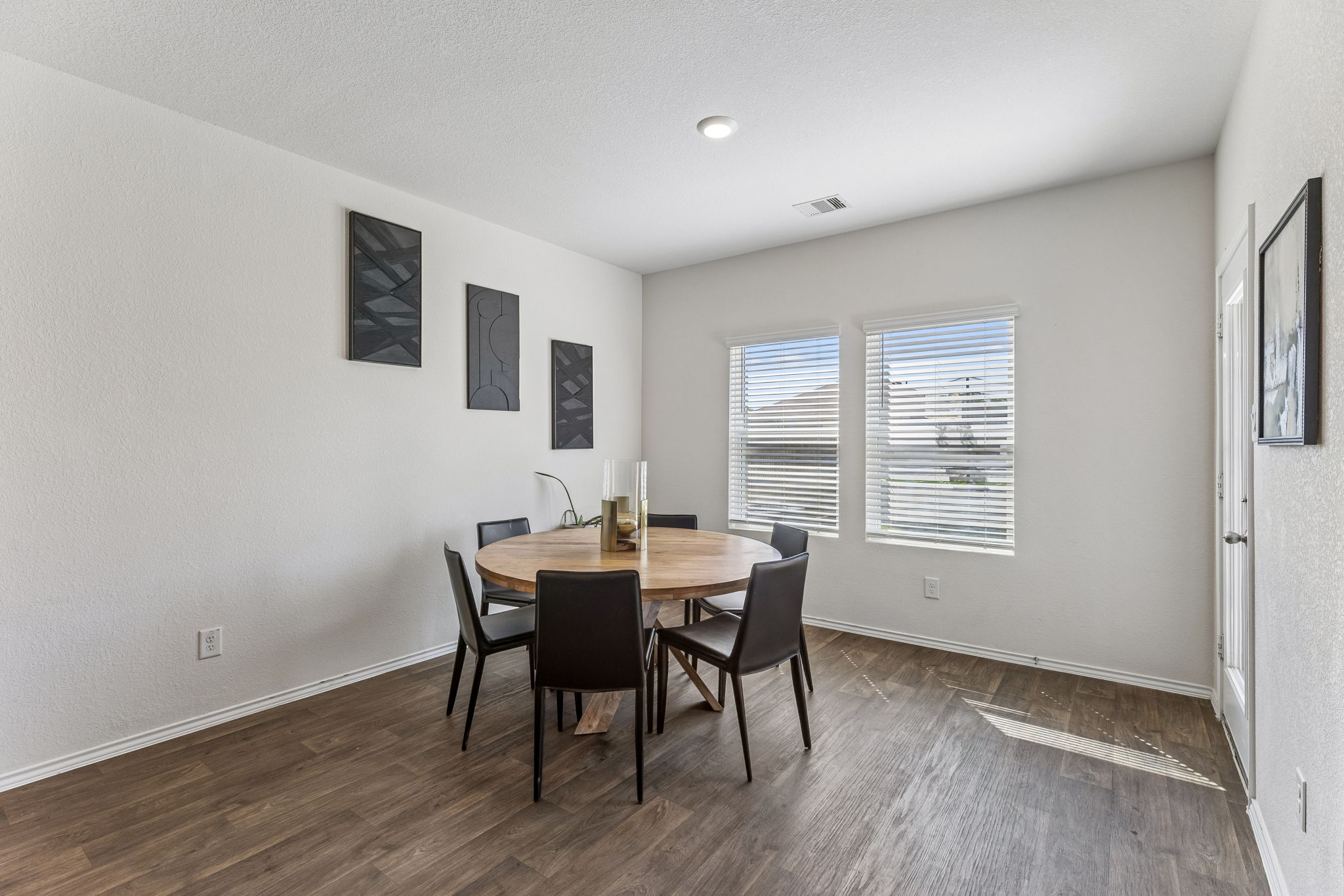 343 Sickle Loop Kyle, TX 78640 - Photo 17 of 40 Dining area featuring wood-finish flooring, two windows with blinds, a recessed ceiling light, and a white paneled door