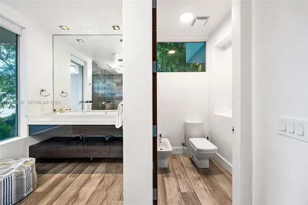 a bedroom with a bed a mirror and a floor to ceiling window