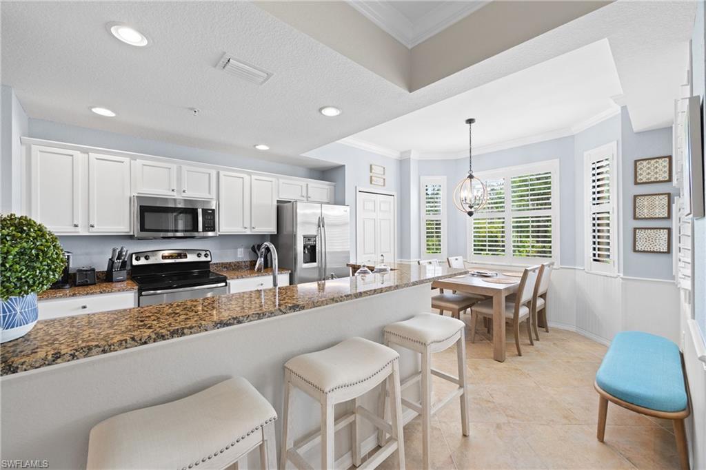 9715 Acqua Court, Unit 116 Naples, FL 34113 - Photo 7 of 43 a large kitchen with granite countertop lots of white cabinets appliances and furniture