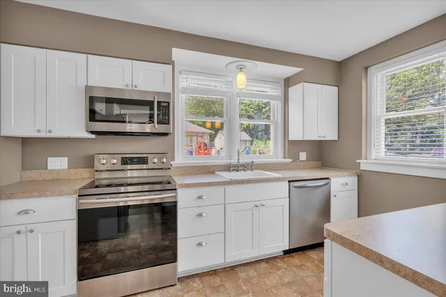 a kitchen with cabinets appliances a sink and a window