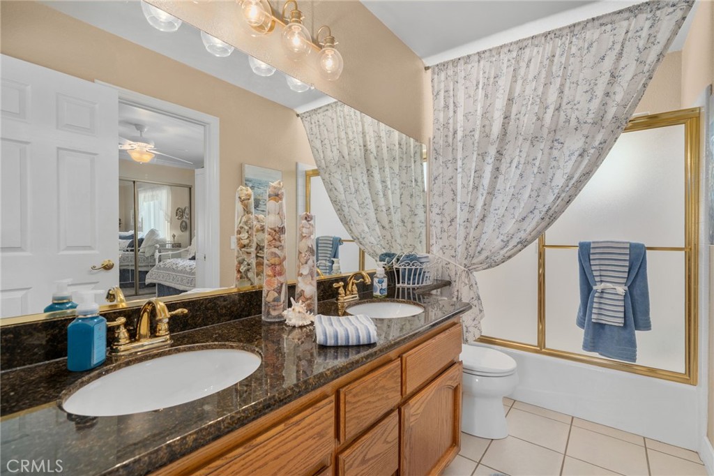 10684 Lakeview Road Yucaipa, CA 92399 - Photo 47 of 63 a bathroom with double vanity sinks a toilet a mirror and shower