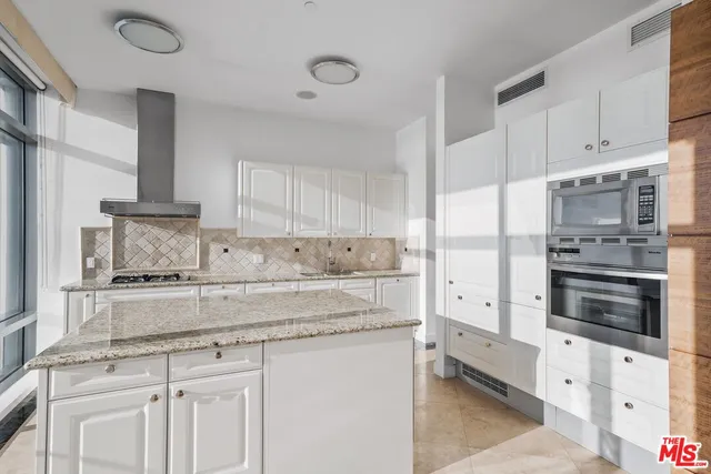 a kitchen with granite countertop white cabinets and stainless steel appliances