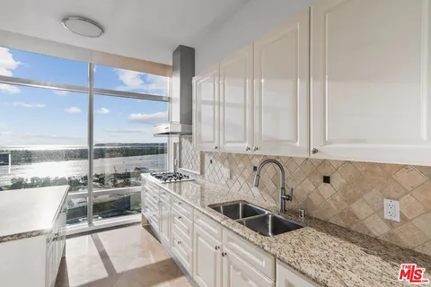 a kitchen with stainless steel appliances a sink a counter top space and a large window