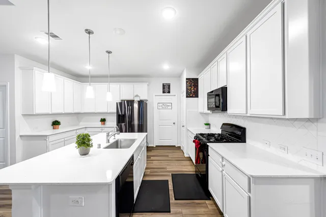 a kitchen with stainless steel appliances a stove sink refrigerator and cabinets