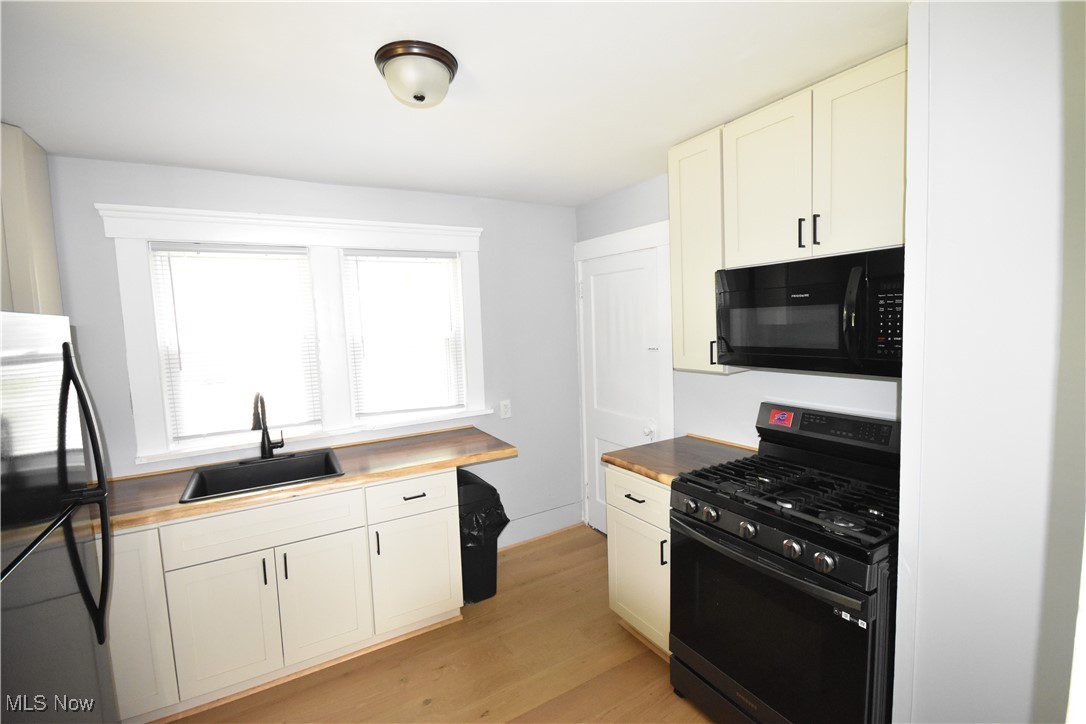 808 West Riddle Avenue Ravenna, OH 44266 - Photo 10 of 28 Kitchen with black appliances, sink, light hardwood / wood-style flooring, and white cabinetry