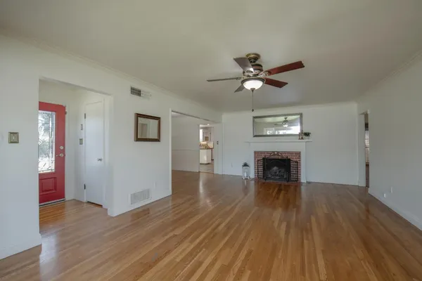 an empty room with wooden floor a fireplace a ceiling fan and wooden floor