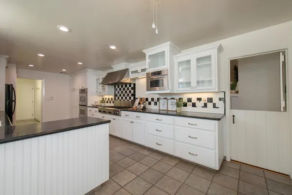 a kitchen with granite countertop white cabinets and stainless steel appliances