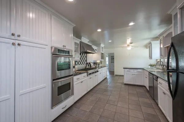 a kitchen with granite countertop a refrigerator and white cabinets