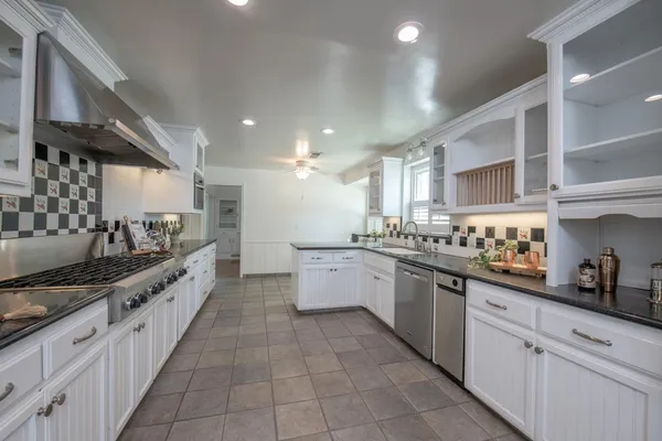 a large kitchen with stainless steel appliances lots of counter space and a sink